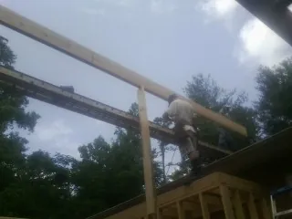 Carpenter setting a ridge beam over a new addition frame — Ice Dam Removal by Roofing Brothers in Belpre