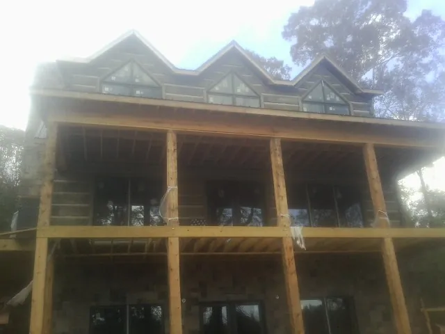 Dormers and porch framing on a large log home under construction — Roof Coating work by our crew in Belpre