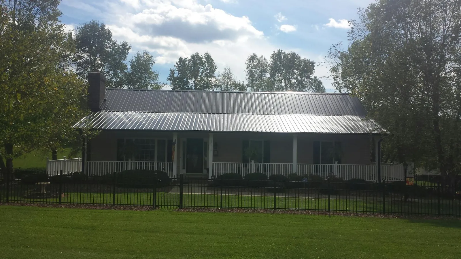 Gray metal roof on a brick ranch with a full width front porch — Gutter Guard Installation work by our crew in Belpre