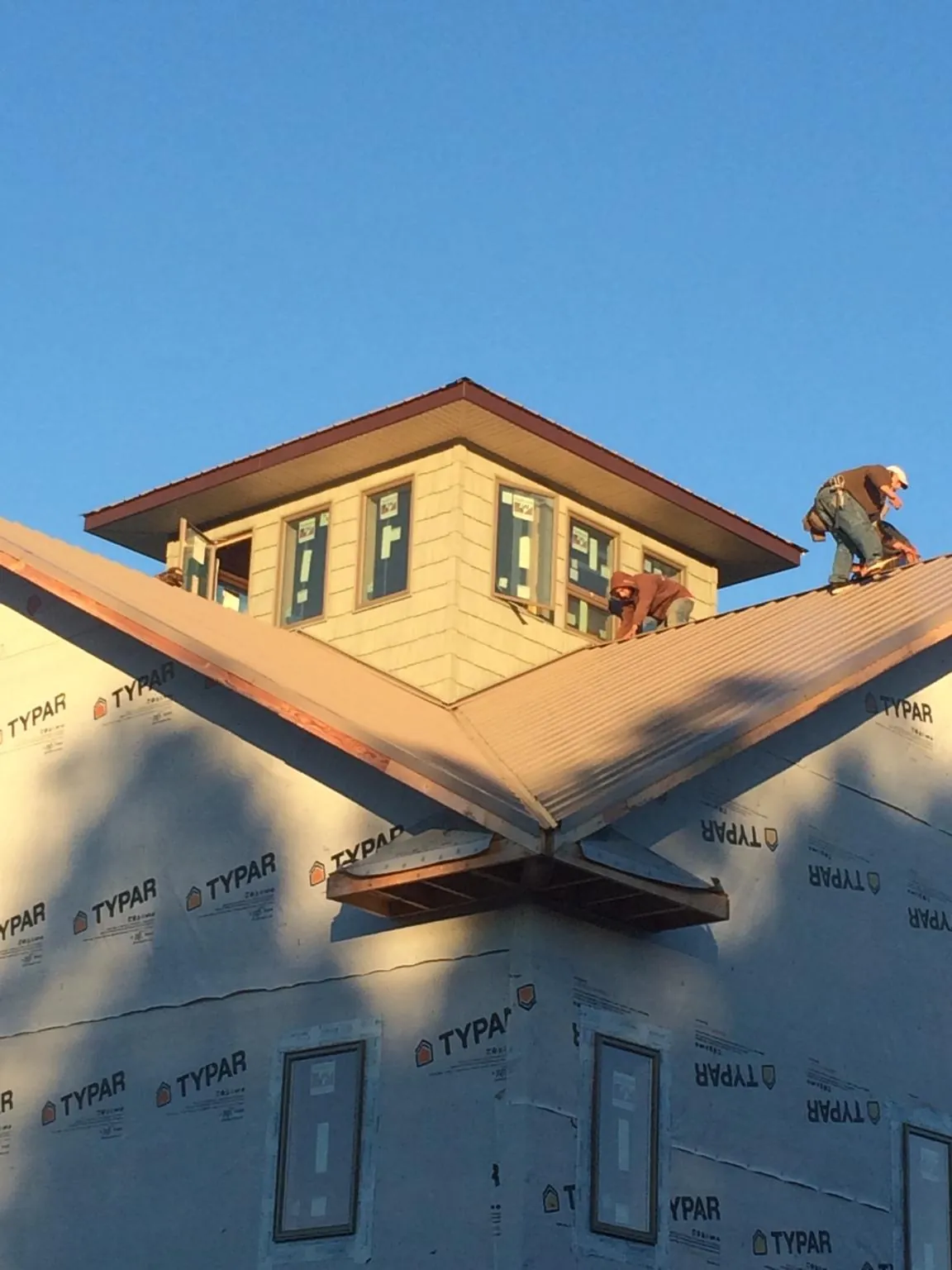 Roofers working around a rooftop cupola on a new metal roof at sunset — Roof Waterproofing in Belpre by Roofing Brothers